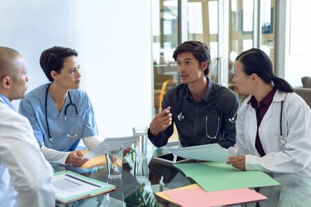 Front view of diverse medical team discussing with each other at the table in hospital. Medical...