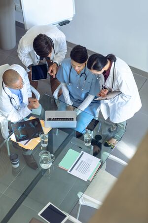 High angle view of diverse medical team discussing over laptop at the table of conference room in hospitalの写真素材