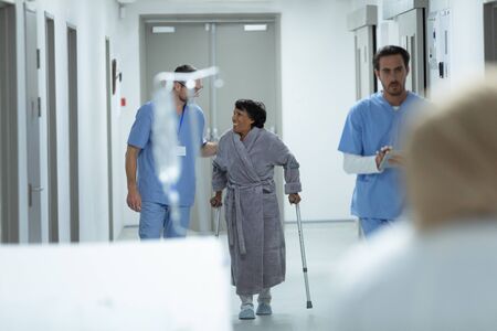 Front view of Caucasian male doctor interacting with disabled female patient in the corridor at hospitalの写真素材