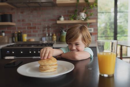 Front view of Caucasian boy having food at dining table in a comfortable homeの写真素材