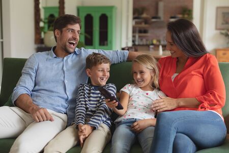 Front view of happy Caucasian family watching television in living room at homeの写真素材
