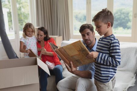 Side view of Caucasian family looking at photo album in living room at home