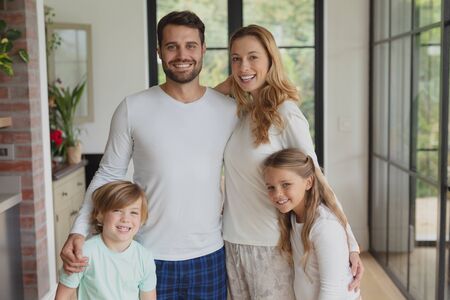 Front view of happy Caucasian family looking at camera while standing in a comfortable home