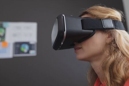 Side view of Caucasian female executive using virtual reality headset in office