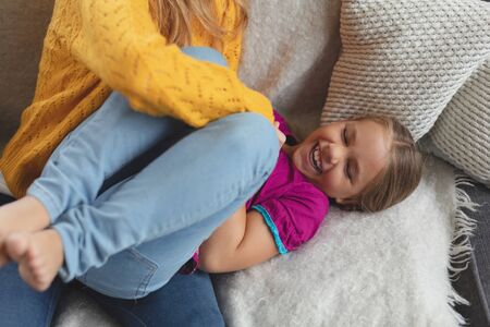 high view of Caucasian mother and daughter having fun on the sofa in a comfortable homeの写真素材