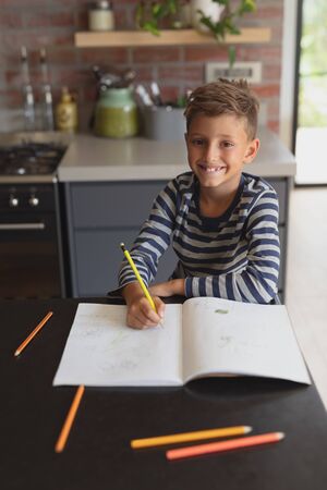 Portrait of Caucasian boy studying at table in kitchen at homeの写真素材