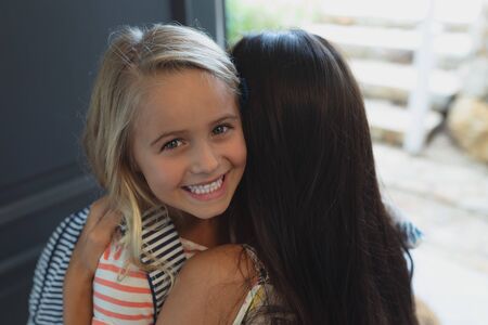 Front view of happy Caucasian daughter embracing her mother in a comfortable homeの写真素材