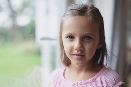 Portrait of Caucasian girl looking at camera near window at homeの写真素材