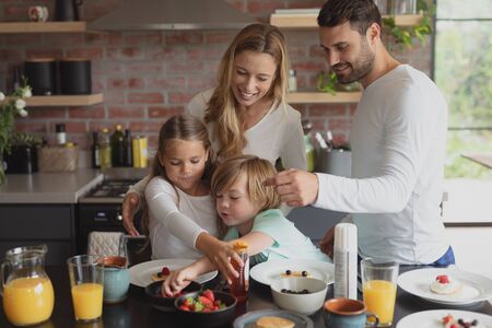 Front view of Caucasian family having food at dining table in a comfortable homeの写真素材