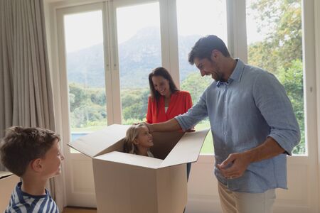 Side view of Caucasian family playing with cardboard box in living room at homeの写真素材