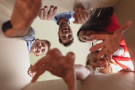Portrait of happy Caucasian family unpacking cardboard box at home