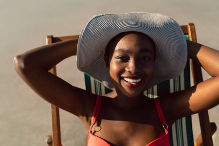 Portrait of happy African-american woman relaxing in a beach chair on the beachの写真素材