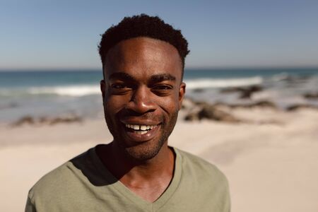 Portait of happy African-american man looking at camera on beach in the sunshineの写真素材