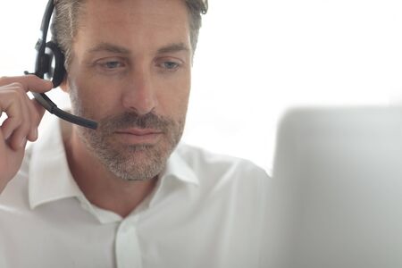 Front view of Caucasian male customer service executive talking on headset at desk in a modern...