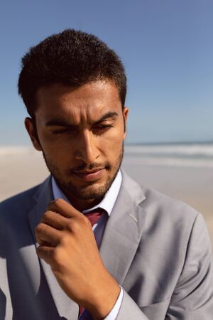 Portrait of thoughtful young Mixed-race Businessman standing on the beachの写真素材