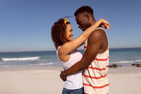 Front view of romantic Mixed-race couple embracing each other on beach in the sunshineの写真素材