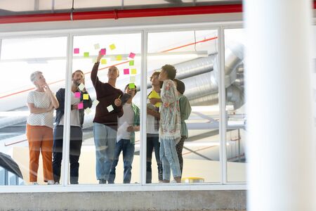 Low angle view of diverse business people discussing over sticky notes in the modern office