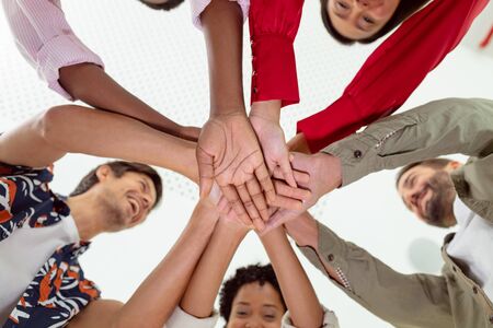 Low angle view of diverse business people forming hand stack in a modern officeの写真素材