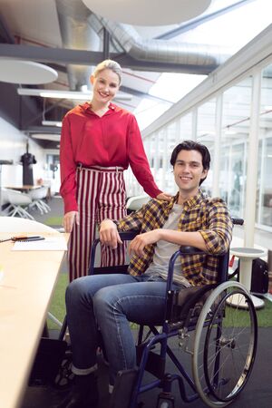 Front view of Caucasian male and female fashion designers looking at camera at desk in officeの写真素材
