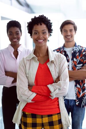 Front view of young diverse business people with arms crossed looking at camera in a modern officeの写真素材