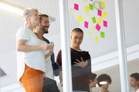 Side view of diverse business people discussing over sticky notes in the modern office