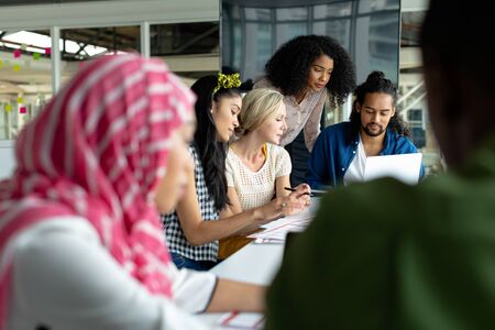 Front view of diverse business people working together on laptop at conference room in a modern officeの写真素材