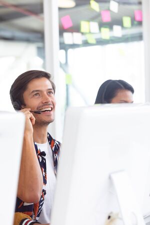 Front view of Caucasian male customer service executive working on computer at desk in officeの写真素材
