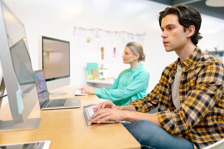 Front view of Caucasian male and female executive working on computer at desk in office