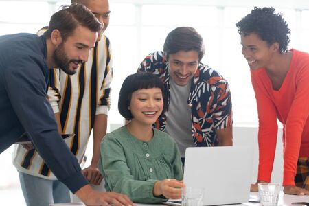 Front view of diverse business people discussing over laptop in the conference room at officeの写真素材