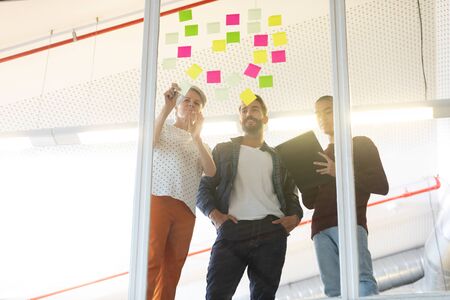 Low angle view of diverse business people discussing over sticky notes in the modern officeの写真素材