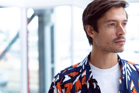 Front view of young Caucasian male businessman looking away in a modern officeの写真素材