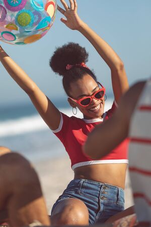 Front view of happy African american woman playing with ball on the beachの写真素材