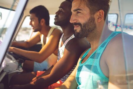 Side view of diverse male friends sitting in a camper van at beachの写真素材