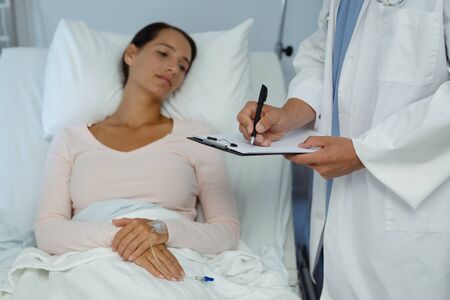 Front view of Caucasian male doctor interacting with female patient in the ward at hospital.