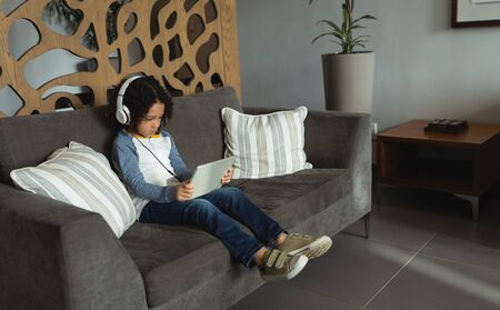 Side view if innocent mixed race boy listening music on digital tablet in the lobby at hospitalの写真素材