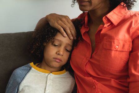 Mid section of mixed race mother consoling her son in the lobby at hospital
