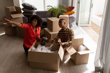 High angle view of African american Couple unpacking cardboard boxes in living room at home
