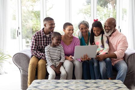 Front view of African american Multi-generation family using laptop on a sofa in living room at homeの写真素材