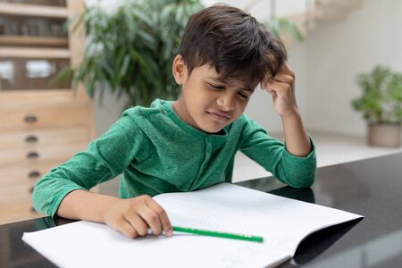 Front view of tensed African american boy doing his homework on a table at homeの写真素材
