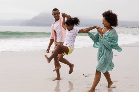 Side view of Happy African american family having fun together on the beachの写真素材