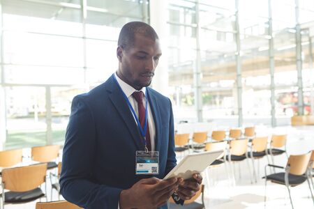 Front view of mature African-american businessman standing in conference room with digital tablet