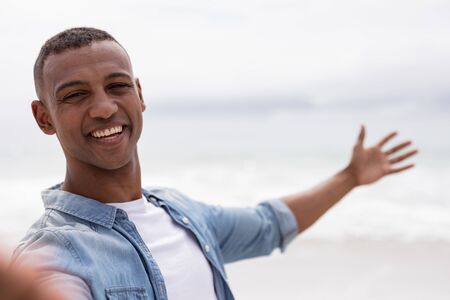 Portrait of African american man smiling at beach on a sunny dayの写真素材