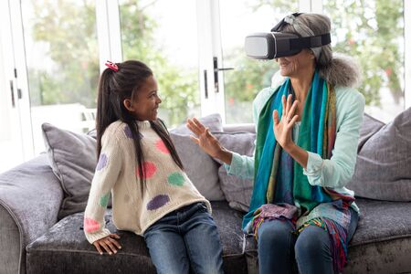 Front view of African american Grandmother with granddaughter using virtual reality headset in living room at homeの写真素材