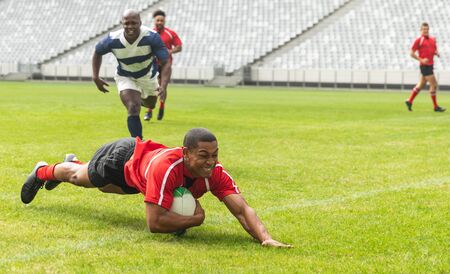 Side view of group of diverse male rugby players playing rugby in stadiumの写真素材