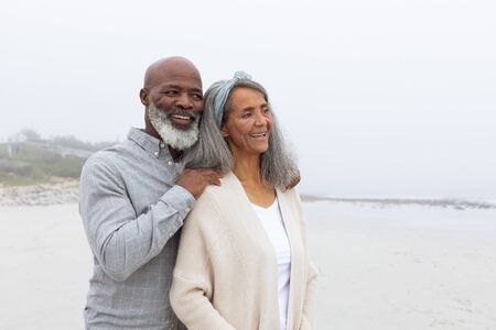 Front view of happy senior African-American couple standing on the beach on cloudy day. Authentic Senior Retired Life Conceptの写真素材