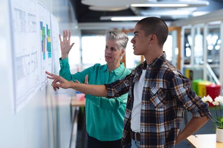 Side view of diverse male and female architects discussing over an architectural plan in office....