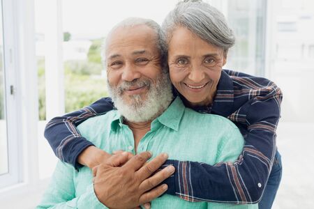 Portrait close up of African-American  couple hugging each other inside a room. Authentic Senior...
