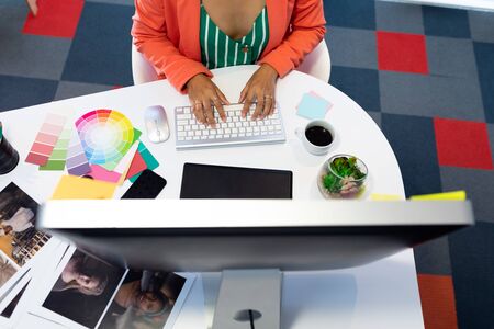 Mid section of young pretty Asian female graphic designer working on computer at desk in office....