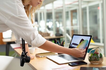 Mid section close-up of Caucasian female graphic designer looking at color swatch in office. This is...