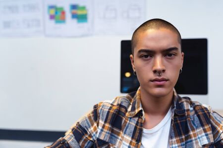 Portrait of disabled mixed race male executive smiling at desk in office. This is a casual creative...